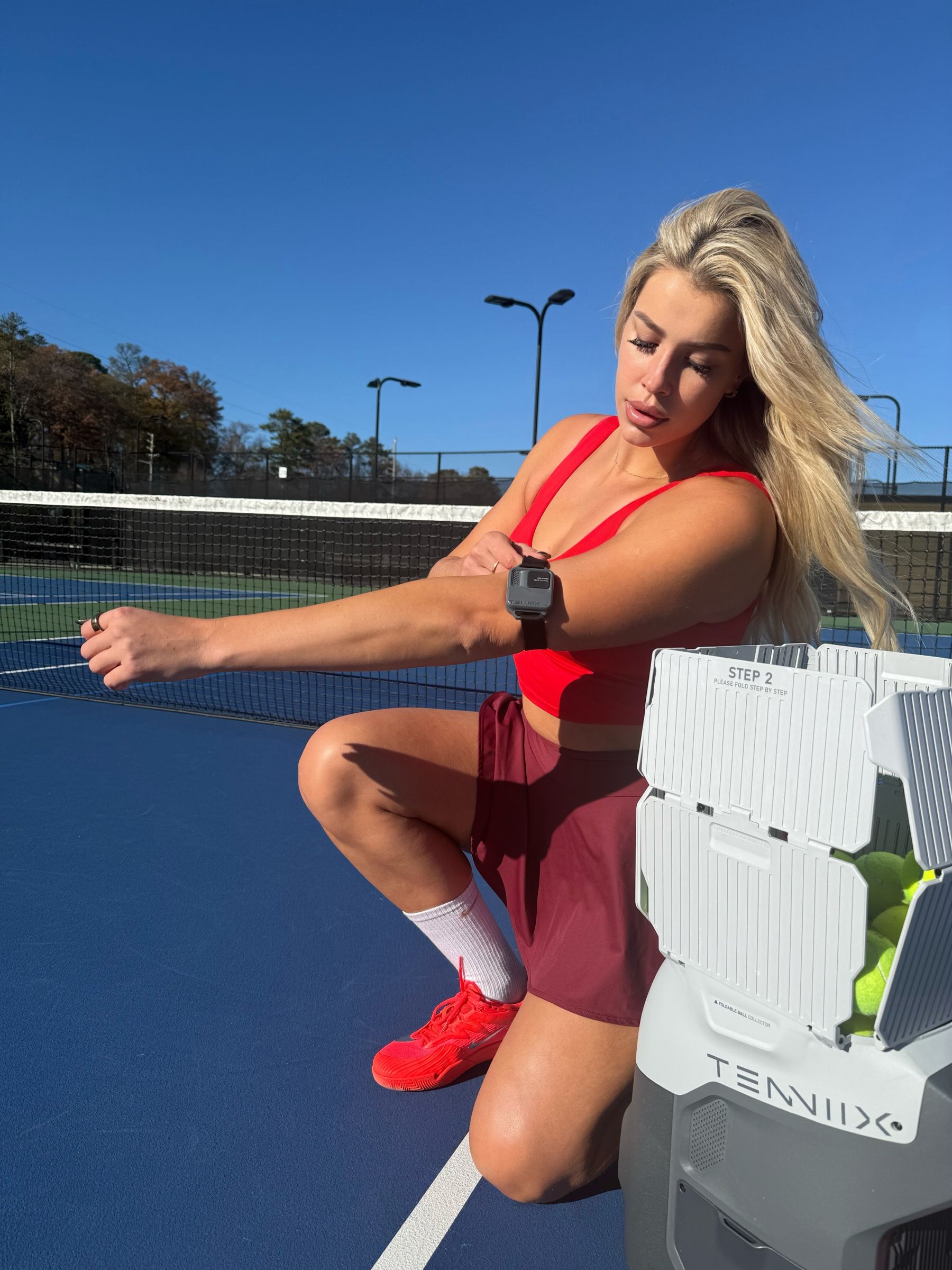 Les on court beside a Tenniix ball machine during a brand integration