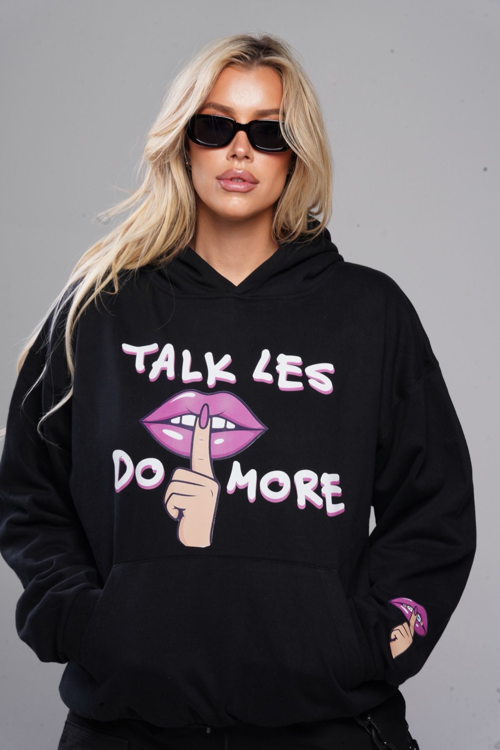 Les in the black Talk Les. Do More. hoodie with the pink hush-lips graphic