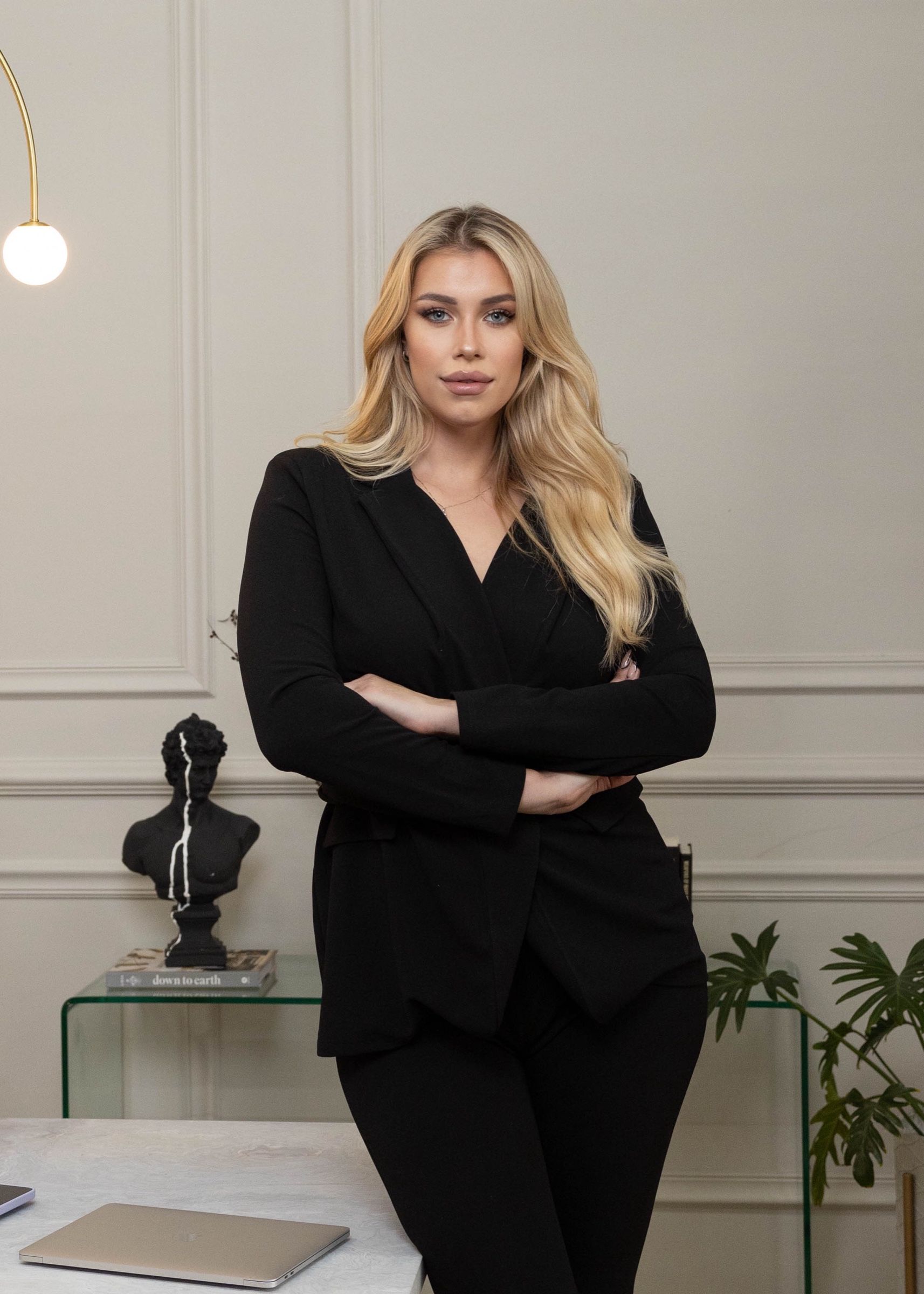 Les in a black blazer, arms crossed, in a bright white office