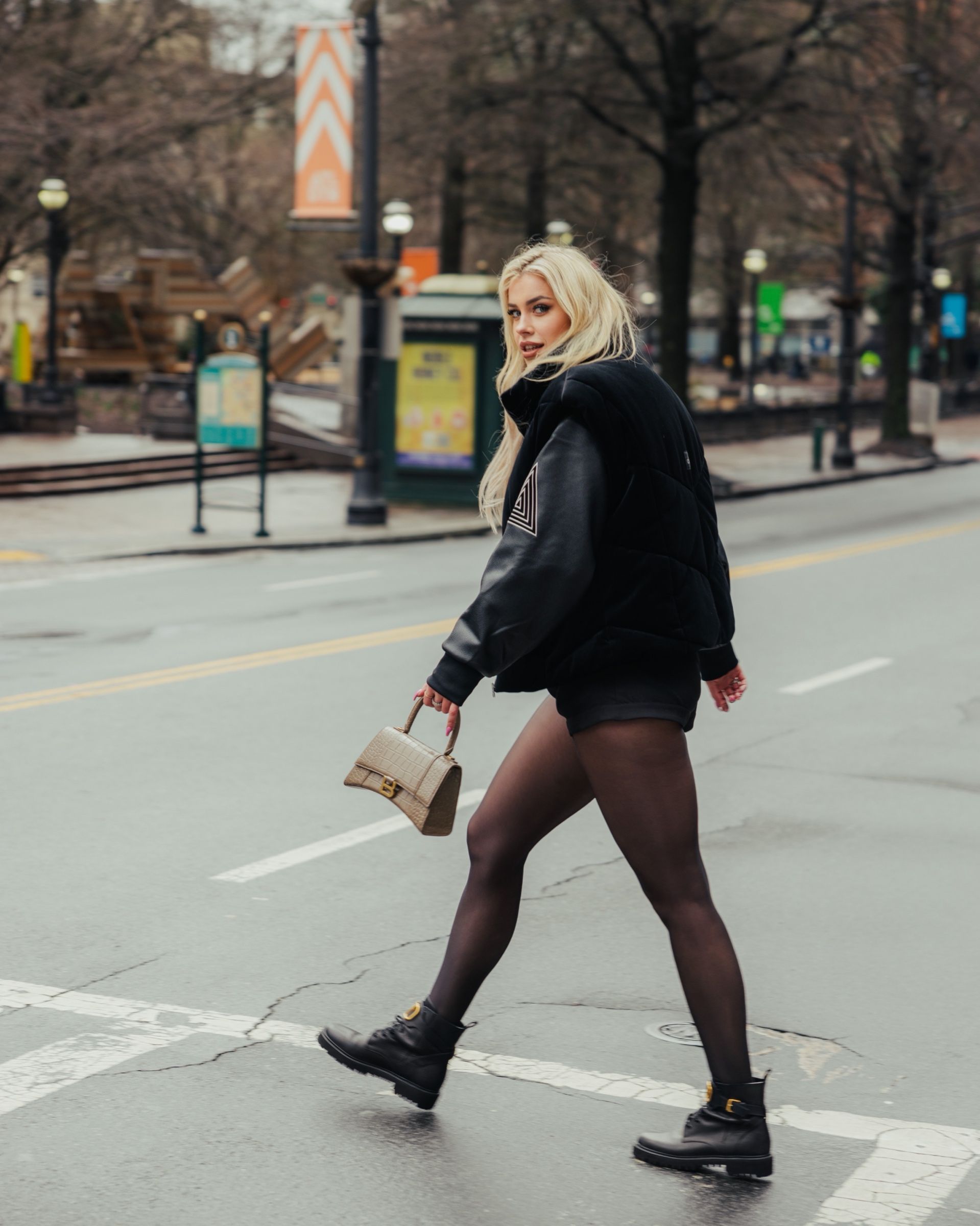 Les crossing a downtown Atlanta street in a black jacket, mid-stride