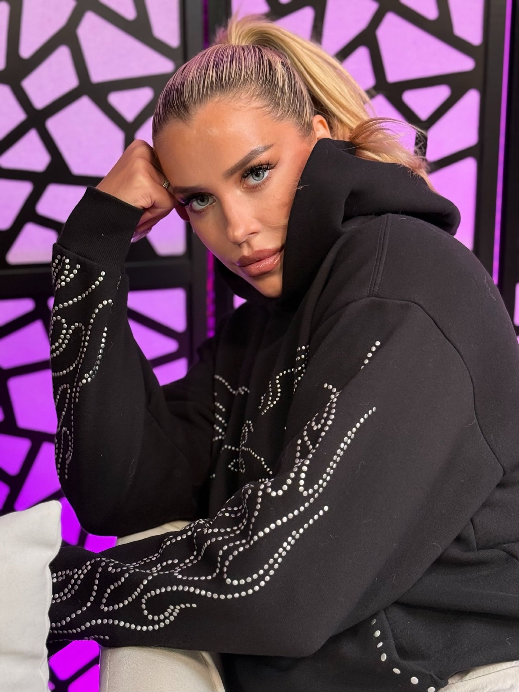 Les in a black embellished hoodie in the violet Talk Les studio, chin on her hand